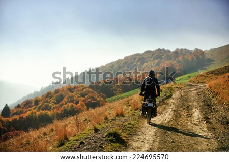 Autumn scene with a motorcycle on a mountain dirt road at golden hour