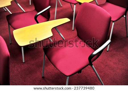 Empty chair with wooden writing area in a conference room