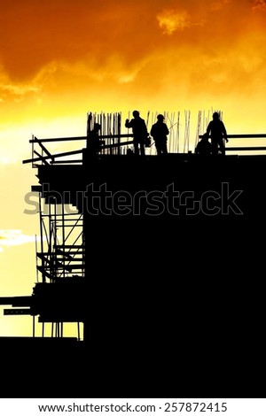 Construction workers silhouettes on a construction site at sunset