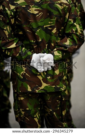 Detail shot with one soldier in camouflage uniform with hands behind his back