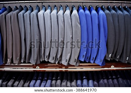 Elegant blue and gray suits on hangers are seen in a suit store