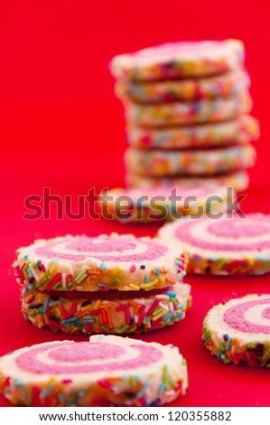 Spiral sprinkled cookies /// A stack of spiral sprinkled cookies on red background