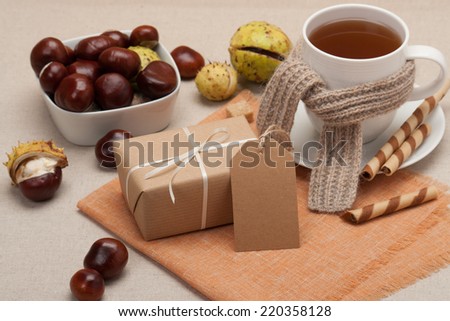 Gift Box With Blank Tag. Cup Of Hot Tea With Sweets. Chestnuts. Natural Linen Table Cloth.