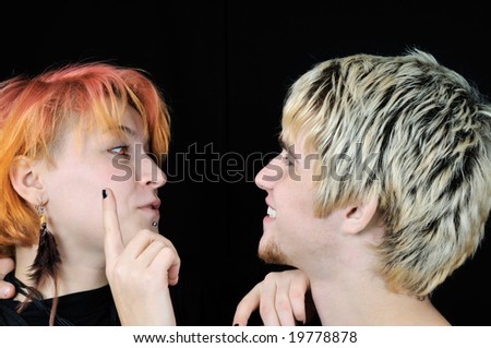 Young informal red-eyed girl wants to touch guy\'s nose, on black background