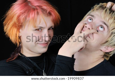 Red eyed young girl scratches out guy's eyes, on black background