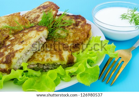 Fried potato pancakes with sour cream, lettuce and greens