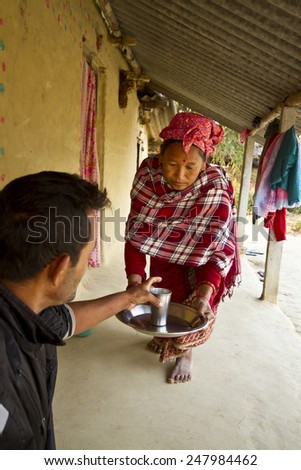 Bardia, Nepal - March 14, 2014: Tharu woman offering tea in nepali terai. In Nepal, tradition wants that woman invite tea at all visitors.
