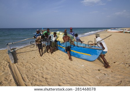 Batticaloa, Sri Lanka- June 24, 2014: Fishermen pushing dugout canoe in Batticaloa, Sri Lanka. They belong to tamil people ethnicity