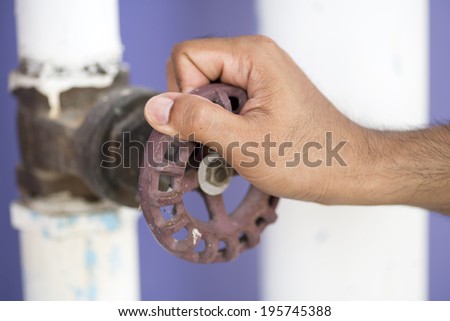 Hands close-up of  manual worker turning cut-off valve at plant