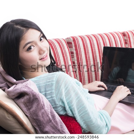 Young cheerful beautiful woman sitting on the sofa with laptop at home