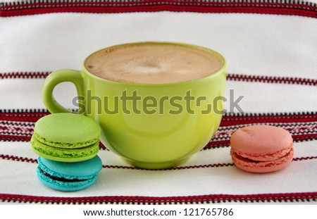 Big green cup with cappuccino and multicolored biscuits