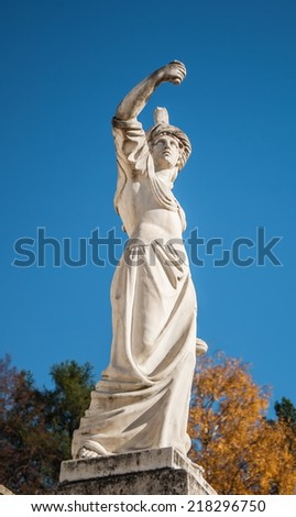 Antique sculpture in the autumn park on a background of blue sky