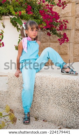 Angry girl in blue denim overalls on background of flowers