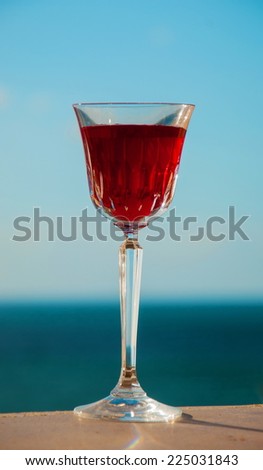 Glass with red wine pomegranate on a background of sky and sea