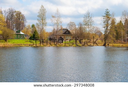 Spring landscape with wooden houses on the river bank