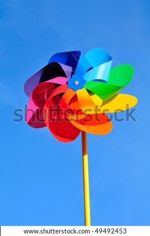 One multi-coloured windmill toy. Blue background.