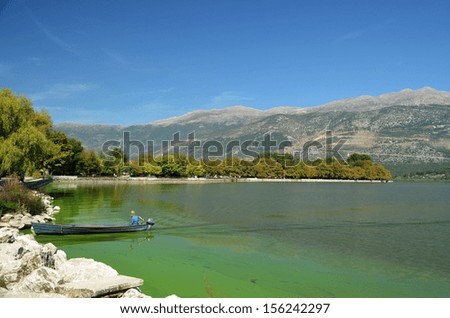 Ioannina  Greece boat fisherman lake Papvotis and mountain Mitsikeli