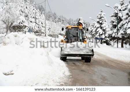snow loader  cleaning road from ice - winter transportation background