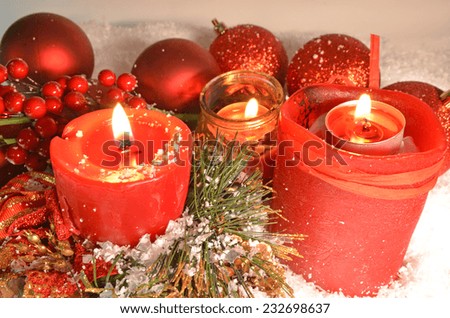 red candles on the snow pine leaves and red xmas balls