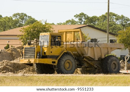 A dump truck sits near a pile of dirt over a weekend break
