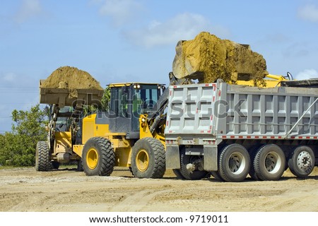 Front end loaders line up to fill a dump truck