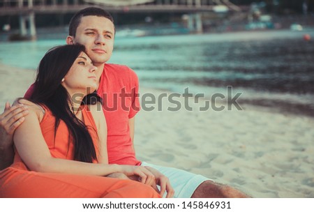 A love story. On the bank of the river, sea. A couple in love. A man and a woman on the beach. Beautiful couple in the sunlight. Against the background of sky and water. Happy boy and girl on nature.