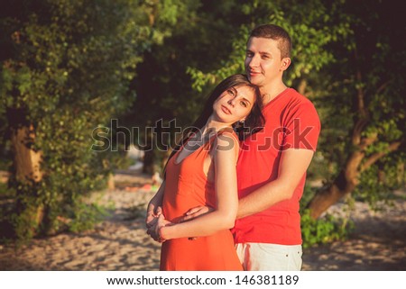 Beautiful young couple man and woman on the nature. Against the backdrop of sand and greenery.