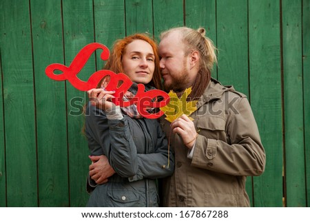 Two young lovers and beautiful people for a walk in the park. Autumn Love Story two. Red hair woman and a man with a beard. Keep love in hands. Writing and love letters. I love you.