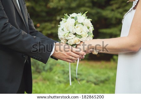 White wedding bouquet of roses in hands of the bride and groom. Bridal bouquet. Wedding decor.