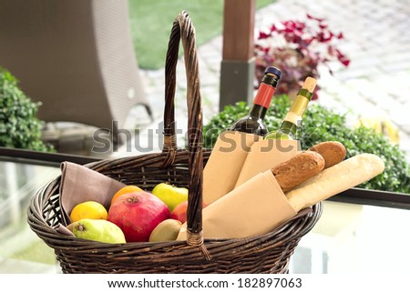 Wicker basket with fruits and vegetables. Basket of bread and wine in the backyard for a picnic.