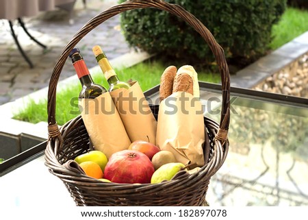 Wicker basket with fruits, vegetables, bread and wine. Basket of bread and wine in the backyard for a picnic.