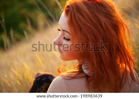 Portrait profile of young modern girl with bright red hair on the background of nature. Young woman hippie style. Girl with eyes closed enjoying the sunshine. blurred background.