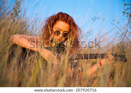 Happy young girl playing guitar outdoors. Rays of the setting sun illuminate a woman musician. Hippie modern movement of the past generation. Music and guitar and fresh air. Sunset summer sun.