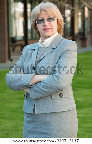 Adult business woman. Woman head small businesses. Portrait of a modern woman experienced leader. Adult woman of retirement age in the glasses. Portrait of a happy senior merchant standing near store.