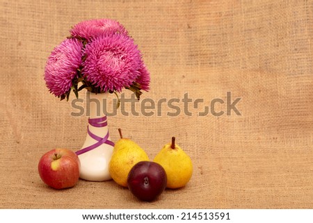 Arrangement of flowers and fruit. Aster flower in white vase on a table stand. Next to them are apple, pear, plum. Autumn still life of fresh fruit and flowers. Composition in yellow tones. Space text
