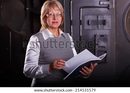 A female engineer. Adult woman working as an engineer at work. Senior Researcher woman holding a book for accounting and statistics of production. Business woman on the background of the turbine.