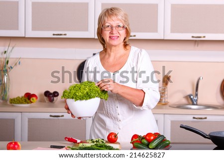 Senior woman cooking in the kitchen. Healthy food - vegetable salad. Diet. Dieting concept. Healthy lifestyle. Cooking at home. Prepare food. woman making salad in kitchen. Beautiful woman at home.