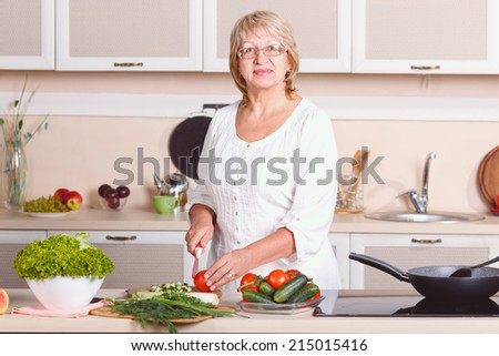 Woman working in the kitchen. Mom while she work something else. Mother prepares a salad. Cooking. Woman while preparing food in kitchen. Beautiful adult multiracial woman while making salad. Retro.