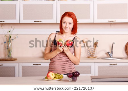Beautiful young woman in the kitchen. Breakfast, kitchen, apple, diet, morning, plum, grape - concept of wellness and a healthy diet of the modern woman. Fresh apples and fruit for morning breakfast.