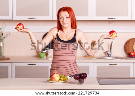 Cheerful girl holding a red apple. Laughter and joy, smile on the face of the woman. Diet, healthy, nutrition, fruits, youth, beauty - concept illustrations for the lifestyle of a modern urban women.