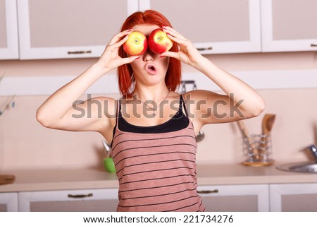 Cheerful good morning in the kitchen. Young woman closes her eyes with apples. Girl holding a red apple. Laughter and joy, smile, diet, healthy, nutrition, fruits, youth, beauty. Concept of lifestyle.