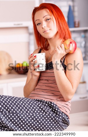Beautiful young woman drinking tea or coffee in the kitchen. Breakfast kitchen, apple, diet, morning tea - the concept of wellness and a healthy diet of the modern woman.The morning breakfast coffee.