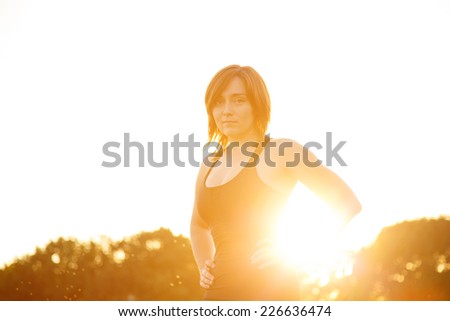 Woman yoga illuminated sun at sunset. Modern young woman in nature in clothing for fitness and yoga classes. Good mood, healthy body, meditation, favorite pastime, happily spending time.