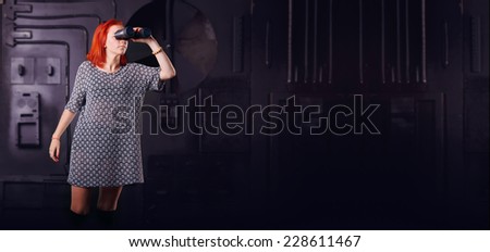 Girl on a background of technology industrial object with binoculars in hand. Modern woman looking through binoculars. Search for anything. Games, fantastic, hero. Concept title page or enter game.