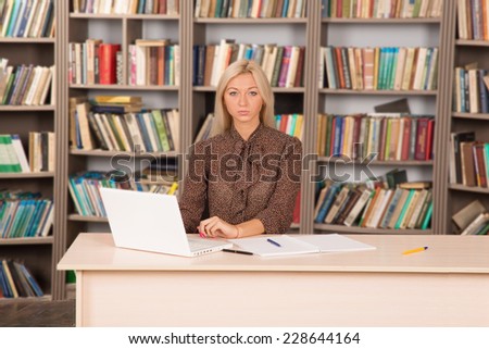 Girl student doing homework in the library. Young modern woman works for his personal laptop computer at table. To get an education at the university. Seriously pursue their studies. Business woman.