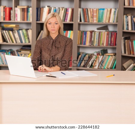 Girl student doing homework in the library. Young modern woman works for his personal laptop computer at table. To get an education at the university. Seriously pursue their studies. Business woman.