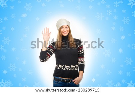 Woman in winter jacket. Beautiful Winter Woman. Young beautiful woman wearing winter clothing on blue background and snow, snowflakes. On winter resort. Hello, Ok and very good. Hello, My name is