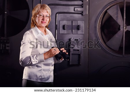 Modern adult business woman looking through binoculars. Woman in business attire holding a pair of binoculars. Watch with binoculars in search of something. Concept screen saver or insurance company.
