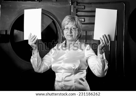 Modern adult business woman holding a two white sheets of paper. Woman in business attire holding a space for records. Universal concept for any advertising. Place for an inscription ad.