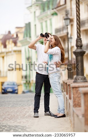 Young couple traveling around the city with binoculars in hand. Man, woman, map, binoculars, city, tourism, holidays - the concept of a modern lifestyle and romantic getaways. Love story of the trip.